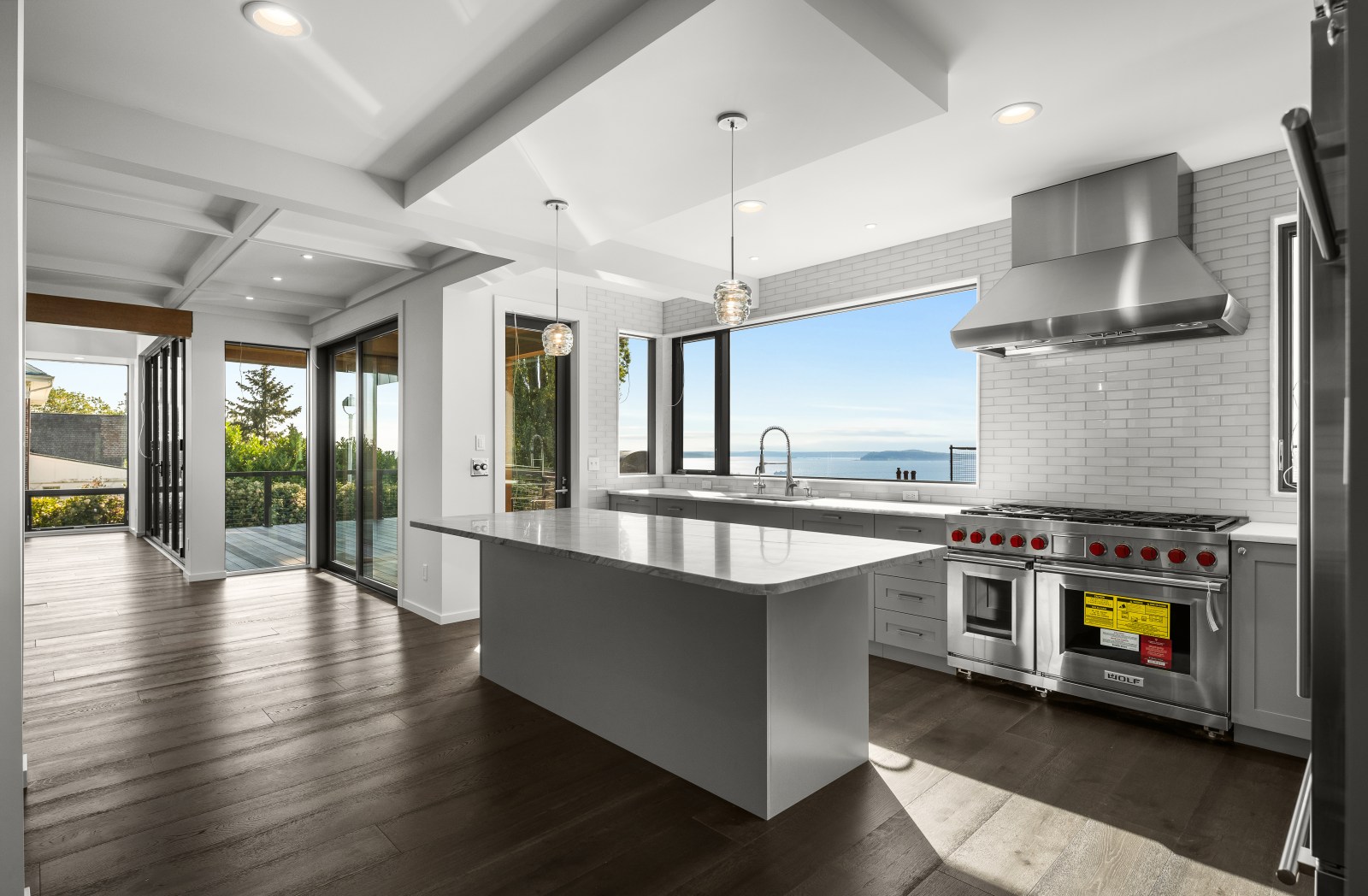 Gray transitional shaker kitchen cabinetry with a custom island, professional range and large picture window