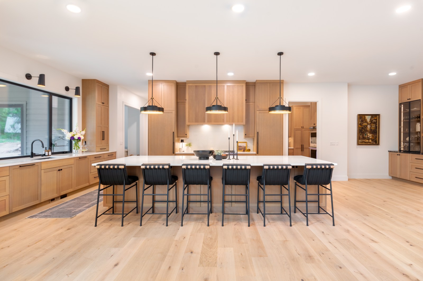 Natural wood shaker custom kitchen cabinetry with a large island, integrated appliances and tailored wood range hood