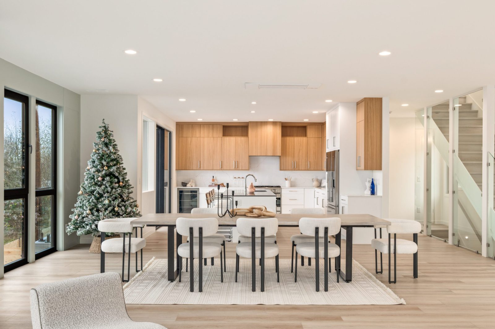 Open modern kitchen with natural wood slab upper cabinets, matte white base cabinets and a compact island