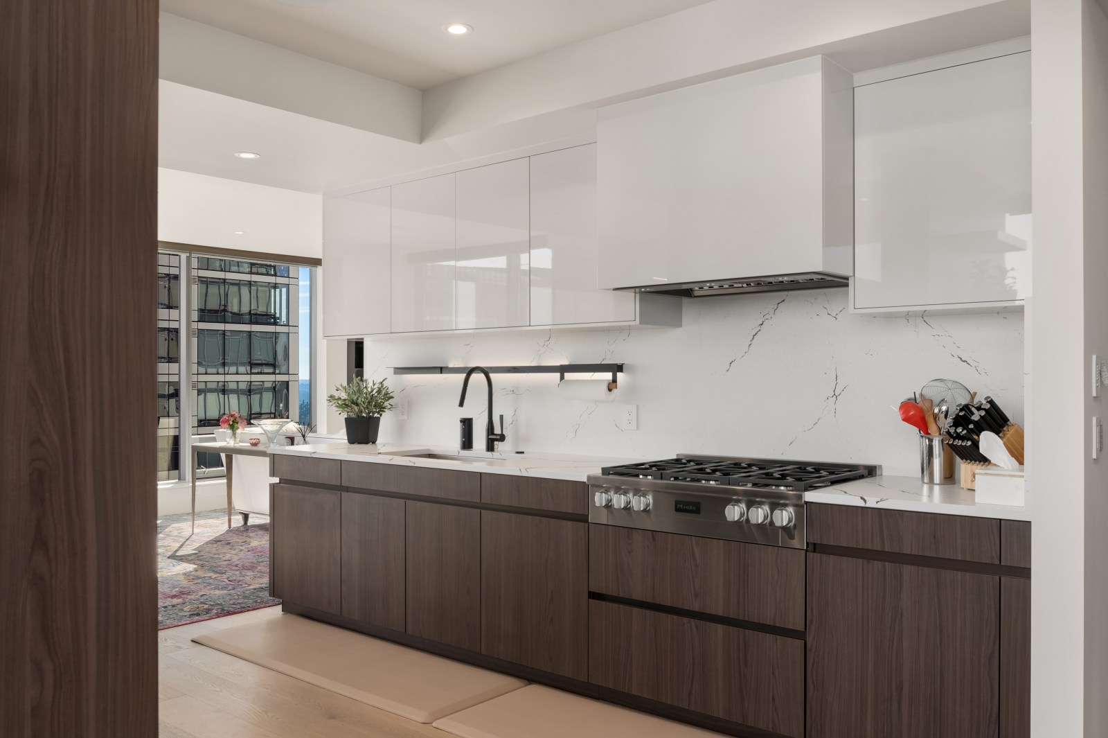 Custom walnut and white gloss kitchen cabinetry with handle-free drawers and concealed ventilation