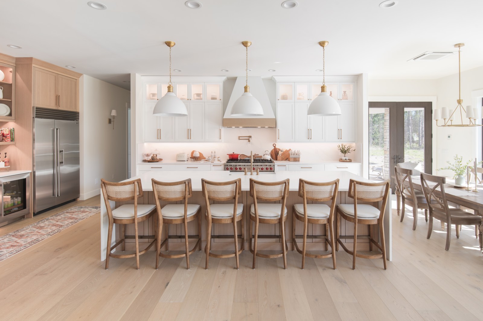 High-end custom kitchen with white shaker cabinets, a white oak island, display cabinets and a tailored range hood