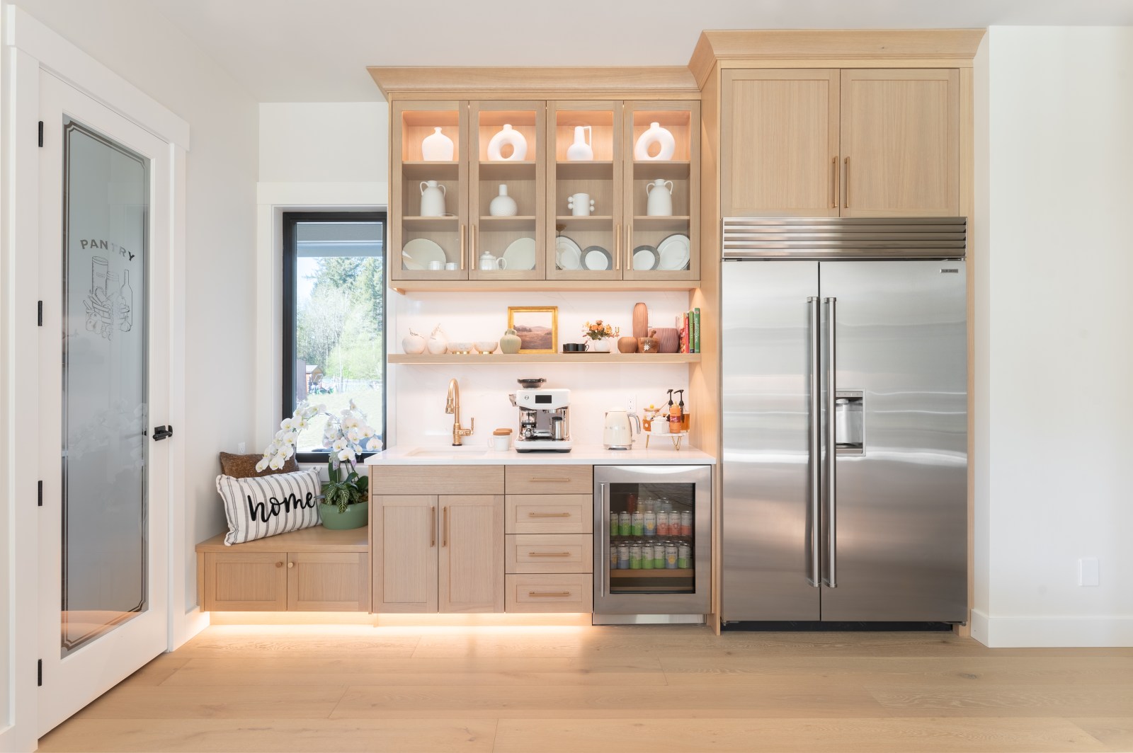 White oak custom kitchen cabinetry with glass-front display storage, beverage center and integrated lighting