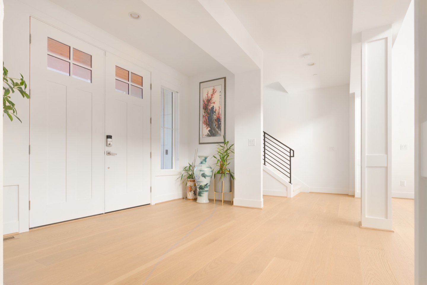 Light wood flooring meeting an entry and staircase in a completed LeviArs remodel