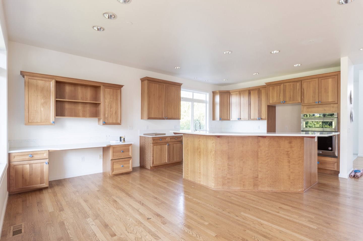Existing Klee kitchen with an angled island, wood cabinetry and large windows before remodeling