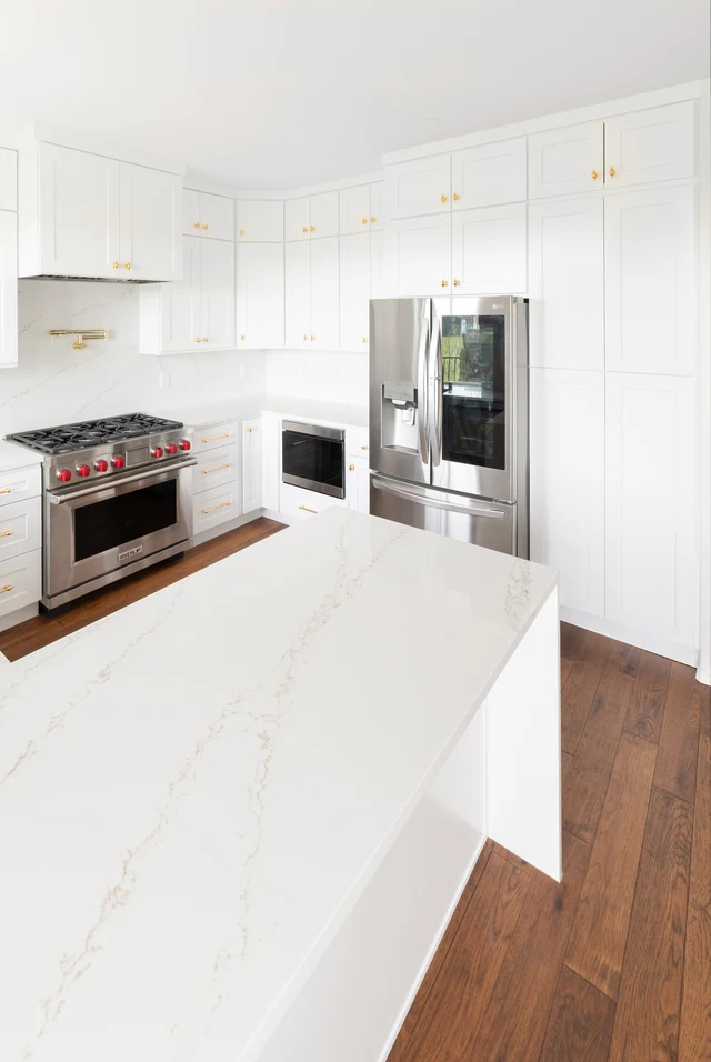 White kitchen cabinetry, stone-look peninsula and stainless-steel refrigerator