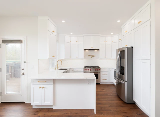 White kitchen peninsula facing tall cabinets and glazed exterior door