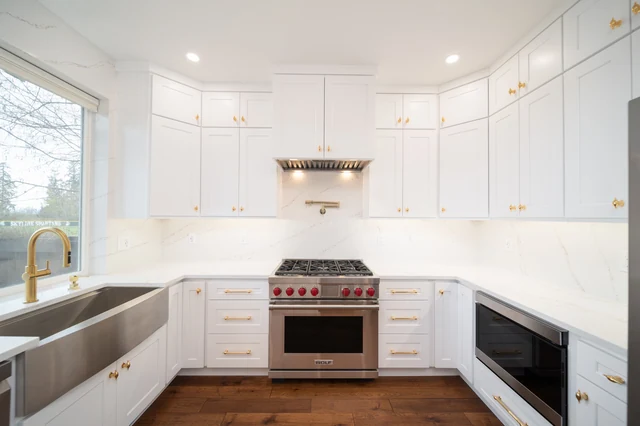 White kitchen cooking wall with range hood, brass hardware and farmhouse sink