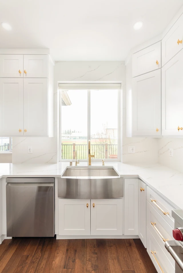 Window-facing farmhouse sink with integrated white base cabinetry