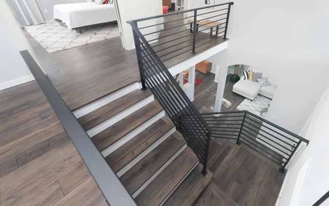 Split staircase with gray treads and black horizontal metal railings
