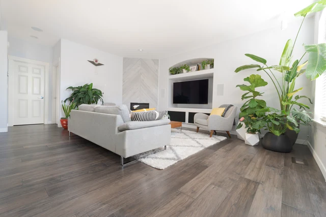 Living room with gray flooring, fireplace wall and large houseplants