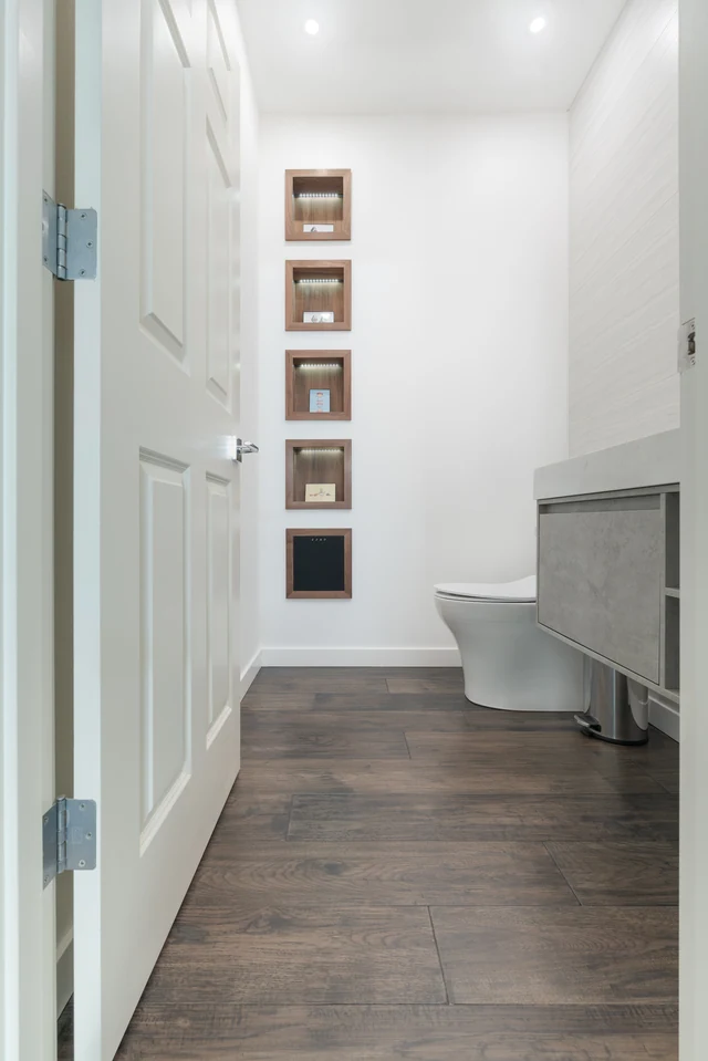 Gray floorboards continuing into a compact bathroom with floating vanity