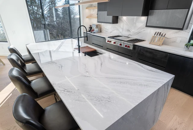 Veined waterfall island countertop with an inset sink and adjoining kitchen work surfaces in a LeviArs remodel