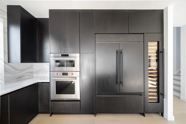 Dark refrigerator panels, stacked ovens and narrow bottle storage