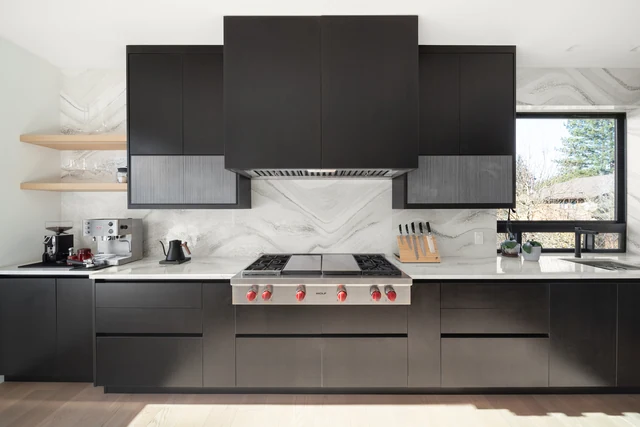 Dark cooking wall with gas range and boldly veined backsplash