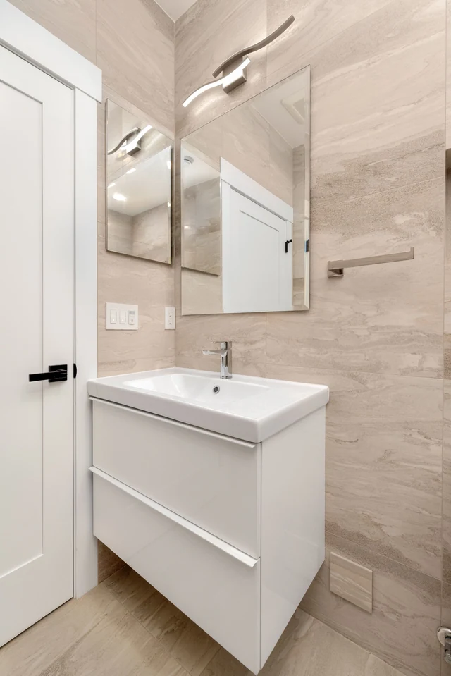 White bathroom vanity, mirrored cabinet and tiled shower