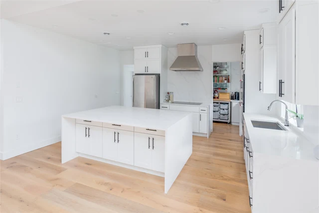 White kitchen island with open storage and wood flooring
