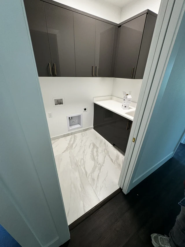 Bathroom entry showing the transition from dark wood flooring to light marble-look porcelain tile