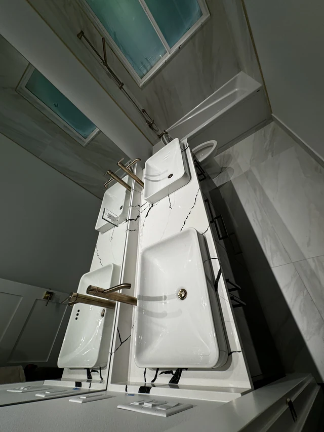 Twin vessel sinks with brushed brass faucets on a black-and-white stone bathroom countertop