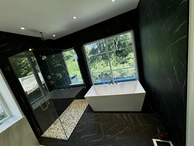 Completed LeviArs bathroom with a freestanding tub beside a dark porcelain shower and garden windows