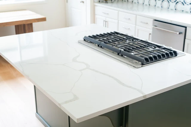 Gas cooktop set into a white veined island countertop