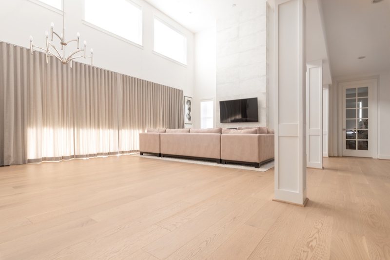 Whole-home remodel with light oak flooring, kitchen and connected living spaces, view 2 of 9