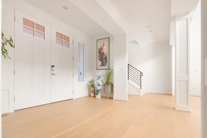 Whole-home remodel with light oak flooring, kitchen and connected living spaces, view 4 of 9