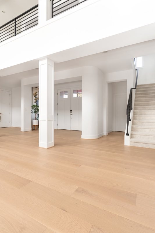 Whole-home remodel with light oak flooring, kitchen and connected living spaces, view 6 of 9