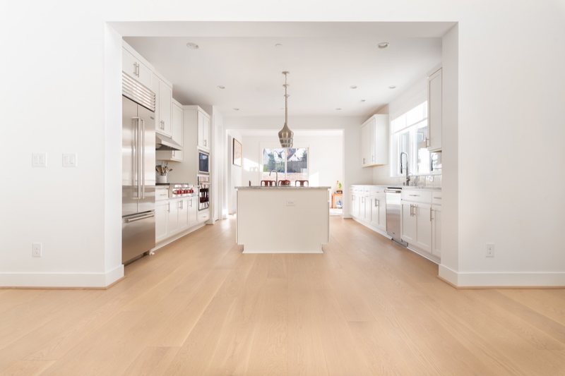 Whole-home remodel with light oak flooring, kitchen and connected living spaces, view 7 of 9