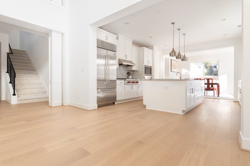 Whole-home remodel with light oak flooring, kitchen and connected living spaces, view 8 of 9
