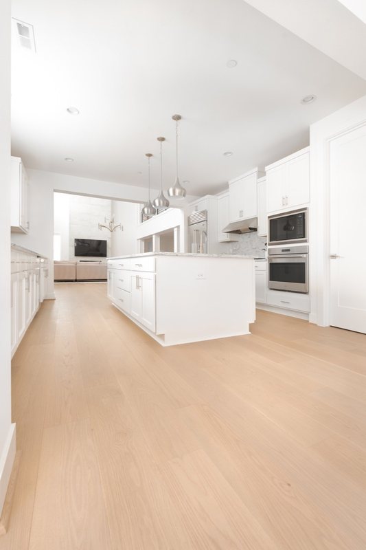 Whole-home remodel with light oak flooring, kitchen and connected living spaces, view 9 of 9