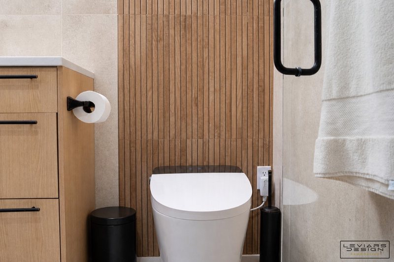 Warm modern bathroom with wood-look tile and black fixtures, view 1 of 8