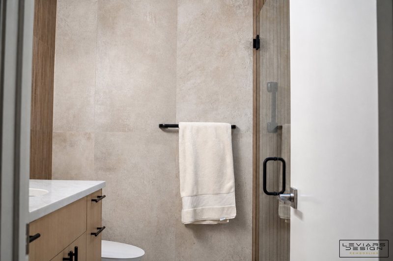 Warm modern bathroom with wood-look tile and black fixtures, view 7 of 8