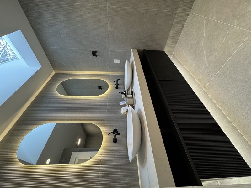 Modern remodeled bathroom with coordinated tile, lighting and storage, view 5 of 9