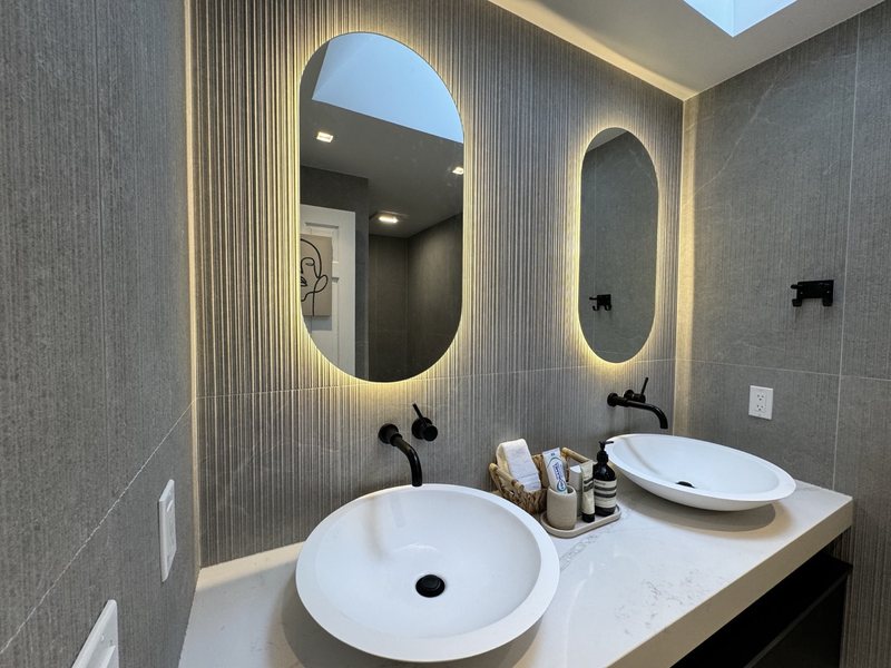 Modern remodeled bathroom with coordinated tile, lighting and storage, view 6 of 9