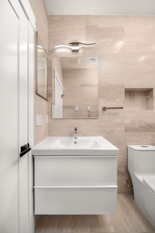 Stone-look bathroom with a white vanity and glass shower