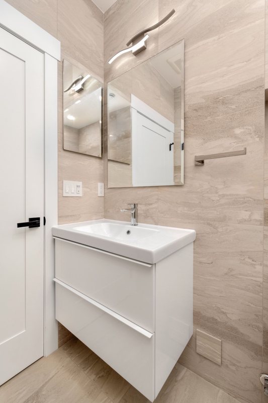 White bathroom vanity, mirrored cabinet and tiled shower