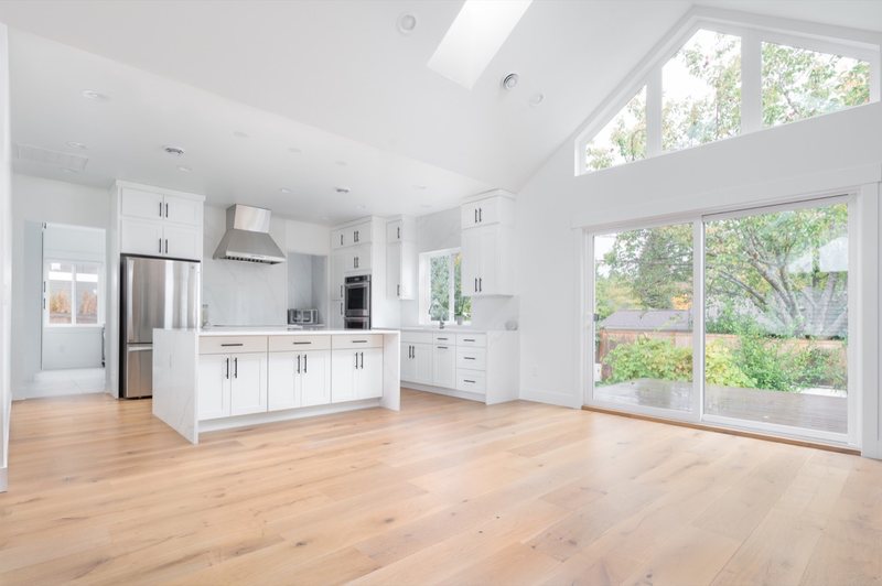 Bright open kitchen with white cabinetry and natural wood flooring