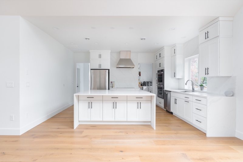White kitchen island, cabinetry and stainless-steel range hood