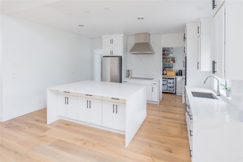 White kitchen island with open storage and wood flooring