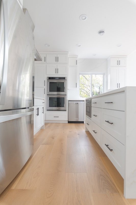 Kitchen walkway with white cabinetry and stainless-steel appliances