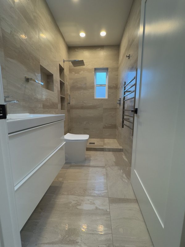 Bathroom vanity and stone-look shower viewed from the doorway