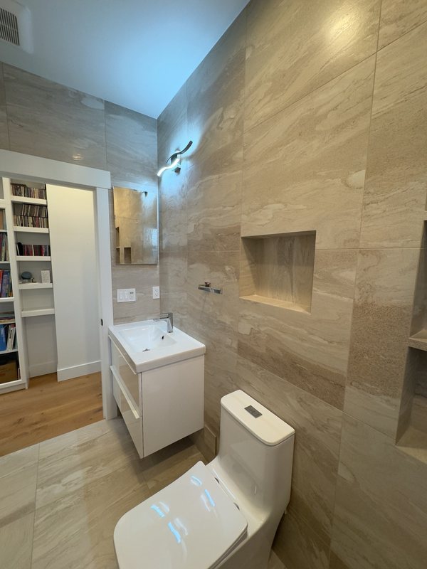 White vanity and toilet against stone-look tile