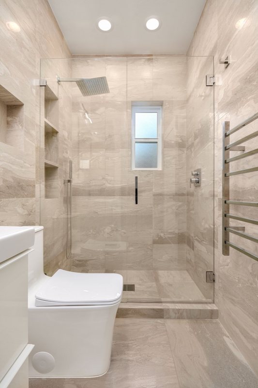 Finished bathroom with white vanity, toilet and glass shower