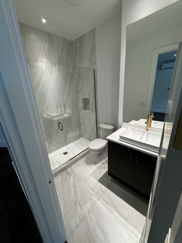 Compact Kirkland bathroom remodel with frameless glass shower, marble-look porcelain floor and white vessel sink