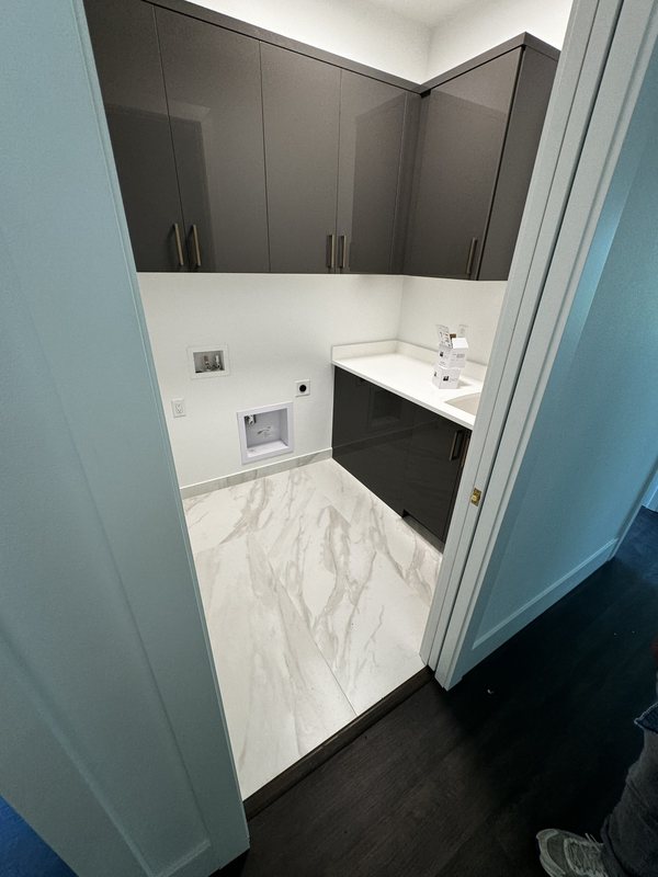 Bathroom entry showing the transition from dark wood flooring to light marble-look porcelain tile