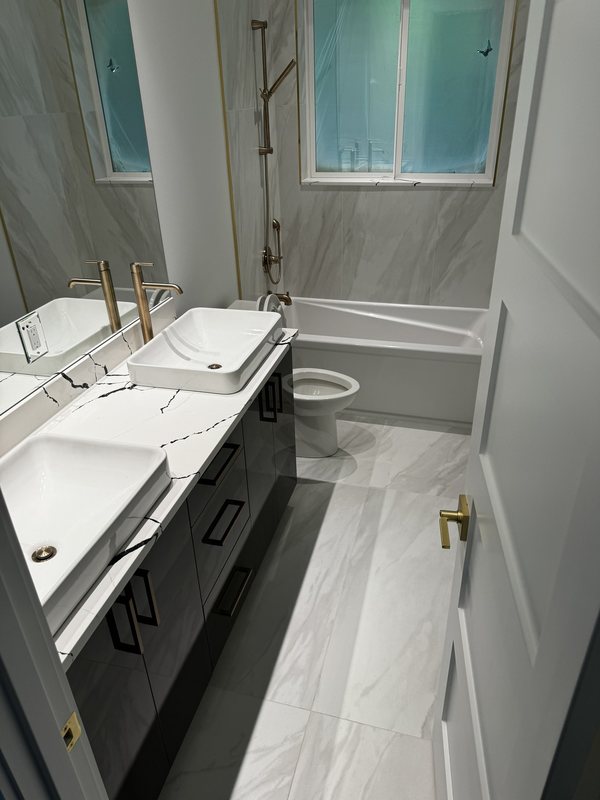 Double bathroom vanity with twin vessel sinks, brass faucets and a freestanding tub beyond