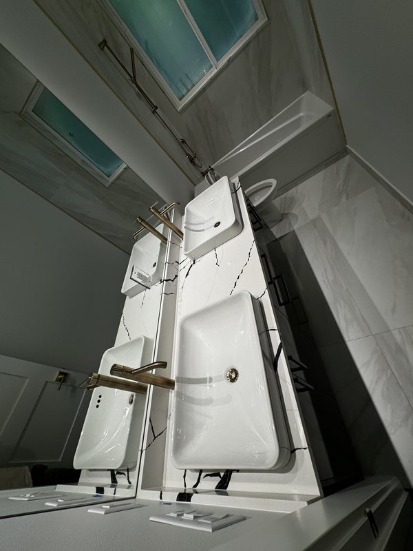 Twin vessel sinks with brushed brass faucets on a black-and-white stone bathroom countertop