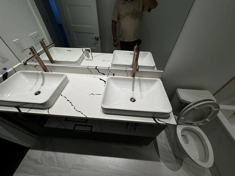 Close view of two white vessel sinks, brass faucets and dramatic veined bathroom countertop