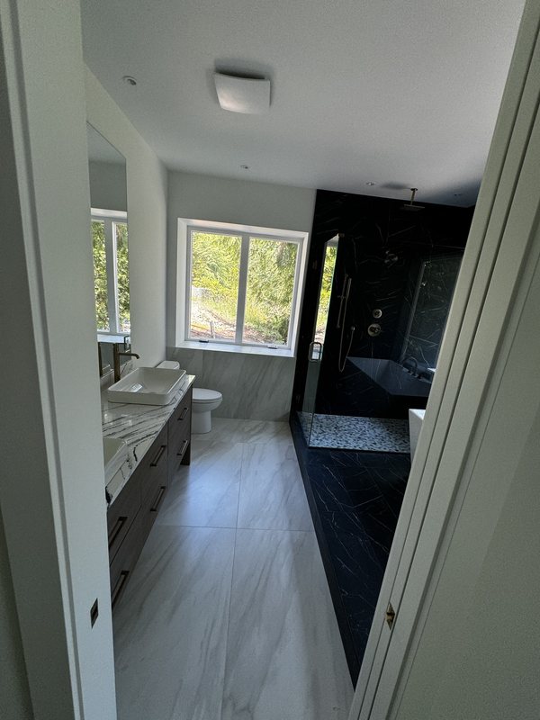 Remodeled primary suite sightline connecting the porcelain-tile bathroom to the adjoining bedroom