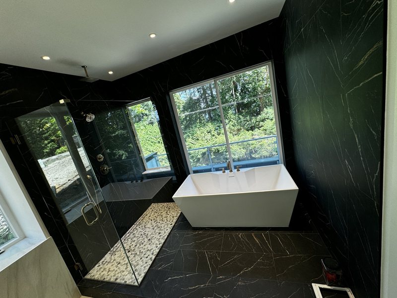 Luxury bathroom wet area with black porcelain walls, pebble shower floor and freestanding soaking tub
